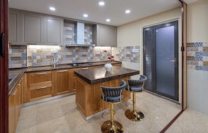 Una cocina moderna con armarios de madera, encimera de mármol y dos taburetes de bar.