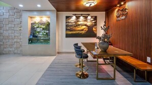 A modern interior with a wooden ceiling, a stone wall, a painting of a sunset, and a sign for 'GTS Apartments'. - Otis Apartment - 457 Rooftop Garden (Ho Chi Minh City)