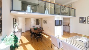 A spacious loft with a dining area, a kitchen, and a balcony with glass railings. - St Gabriel's Loft Apartment (London)
