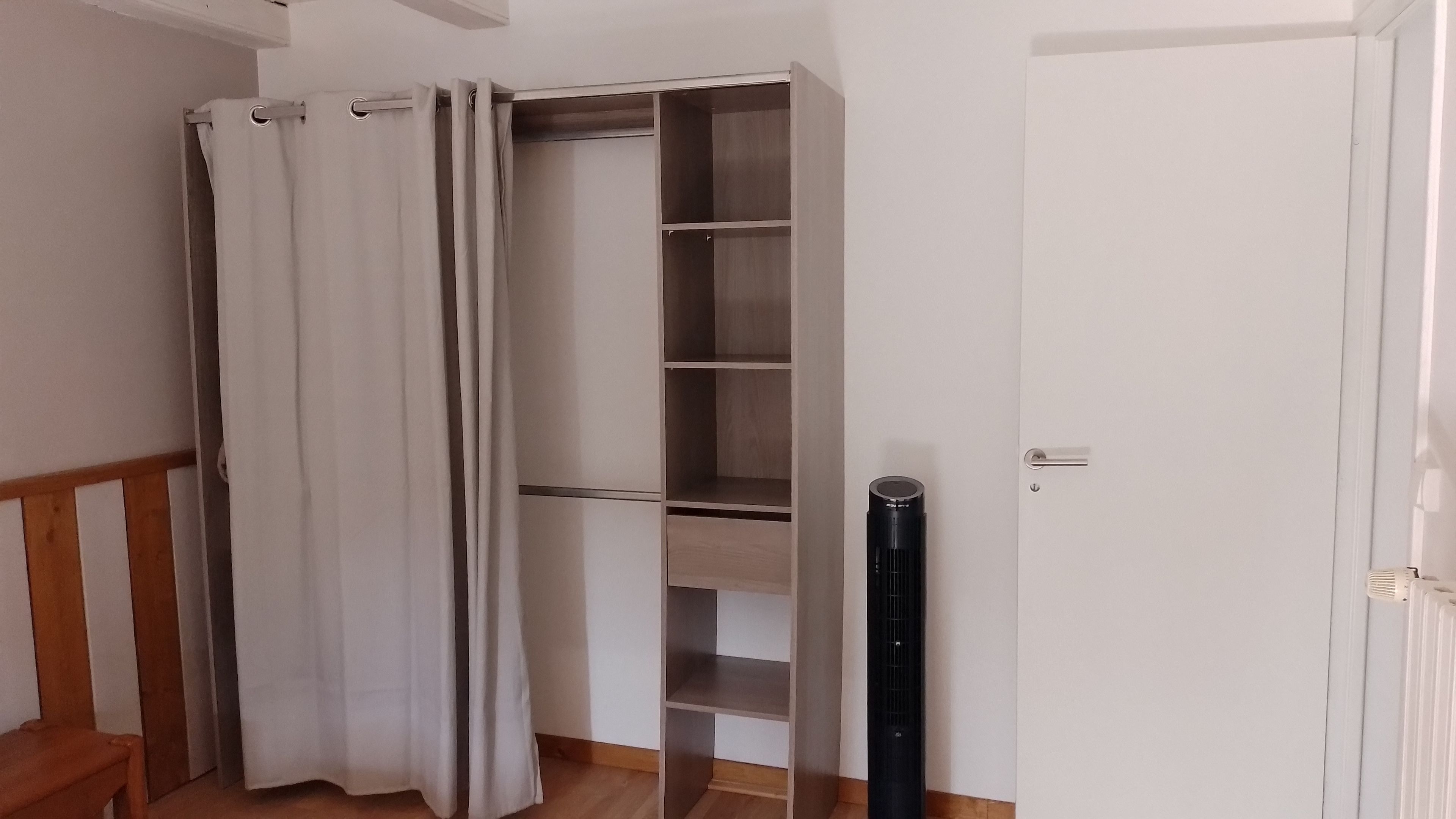 A room with a wooden bench, a white door, and a closet with multiple shelves.