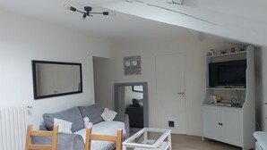 Ett vardagsrum med en soffa, ett soffbord, en tv och ett skåp.