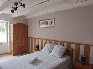 A bedroom with a wooden bed, a nightstand, a wooden wardrobe, a framed picture on the wall, and a ceiling light fixture. - Le nid de la clairière, renovated country house in a quiet, wooded hamlet (Heric)