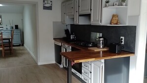 Ett modernt kök med vita skåp, en bänkskiva i trä och en svart stänkskydd.