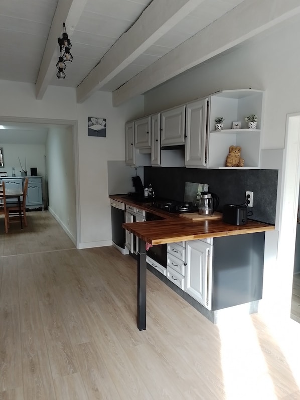 A modern kitchen with white cabinets, a wooden countertop, and a black backsplash. - Le nid de la clairière, renovated country house in a quiet, wooded hamlet (Heric)