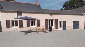 A building with a gravel driveway, a wooden picnic table, and a blue umbrella. - Le nid de la clairière, renovated country house in a quiet, wooded hamlet (Heric)