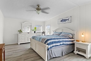 A bedroom with a bed, bedside table, dresser, ceiling fan, and a wall-mounted artwork. - PRIME location!Waterfront River House w dock/lift (Homosassa)