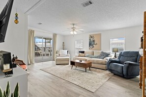 A living room with a sofa, armchair, coffee table, and a ceiling fan. - PRIME location!Waterfront River House w dock/lift (Homosassa)