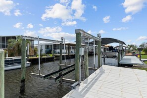 A marina with boats docked, a covered walkway, and a building with a sloped roof. - PRIME location!Waterfront River House w dock/lift (Homosassa)