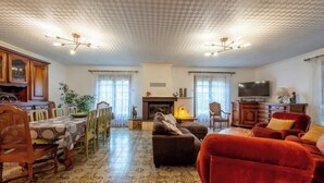 Un soggiorno spazioso con camino, televisione e zona pranzo con pavimento decorato.