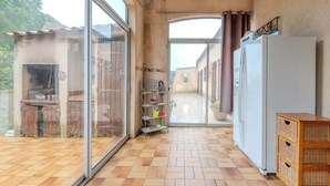 Una cucina con frigorifero, un armadietto in legno e una porta in vetro che dà su un'area esterna.