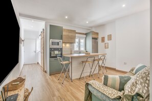 Eine moderne Küche mit Kochinsel, ein Essbereich mit Stühlen und ein Wohnzimmer mit Sofa.