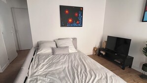 Ein modernes Schlafzimmer mit einem großen Bett, einem Flachbildfernseher und einem Stadtbild an der Wand.