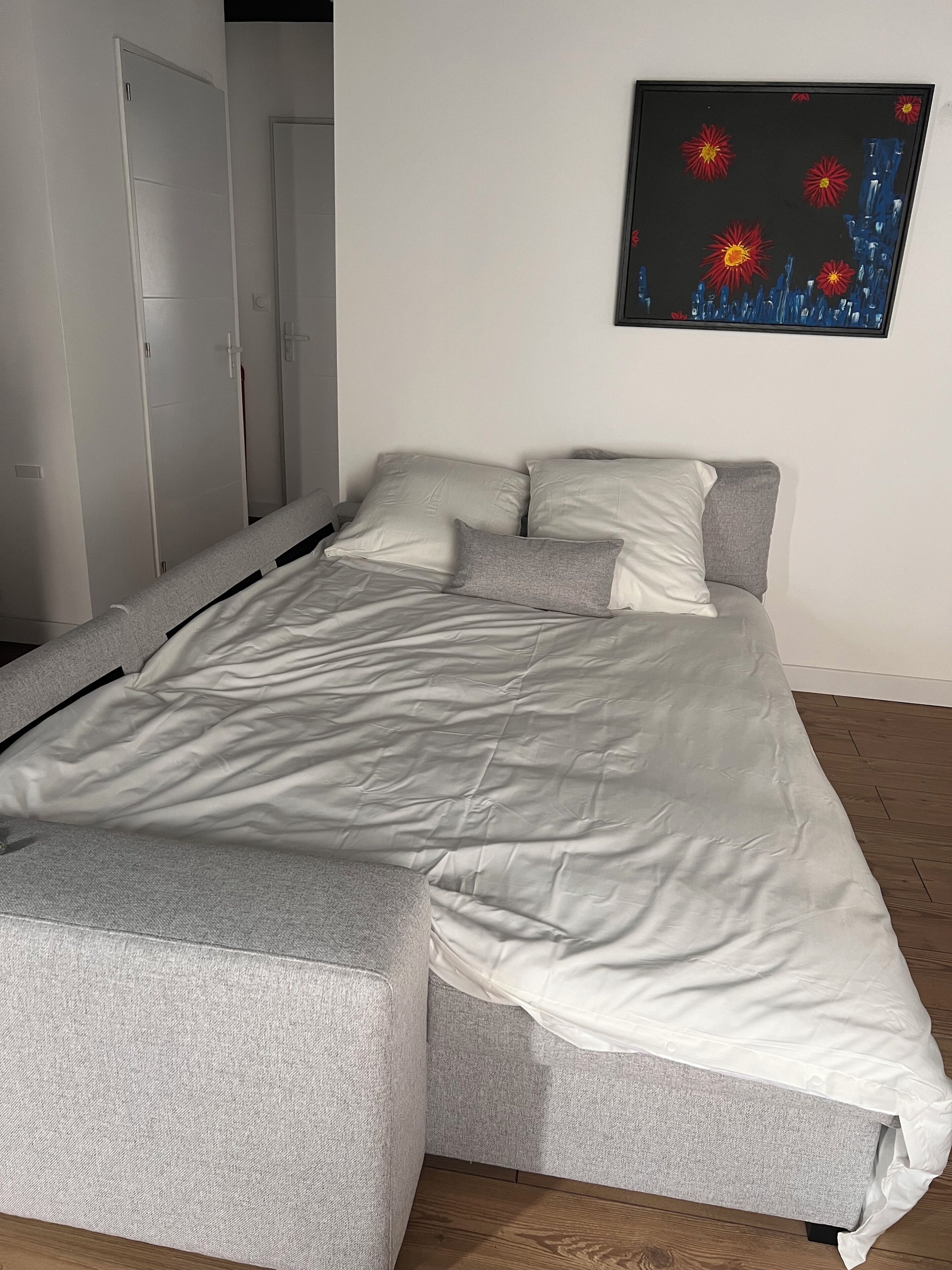 Un lit avec une couette grise et blanche, un oreiller gris et une tête de lit grise.