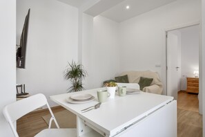 Un comedor minimalista con una mesa blanca, sillas y una pequeña maceta.