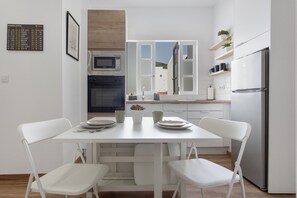 Una cocina moderna con armarios blancos, un refrigerador de acero inoxidable y un microondas.