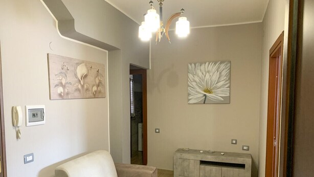 Ein Wohnzimmer mit Sofa, einer Konsolentisch, einer Pendelleuchte und Wandbildern.