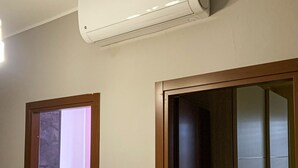 Ein Flur mit einer Decken-Klimaanlage, einem hölzernen Türrahmen und einem durchgehenden offenen Raum.