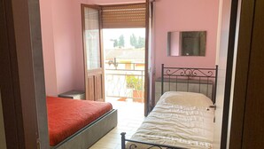 Ein Zimmer mit zwei Betten, einem Fenster und einer Tür, die nach draußen führt.