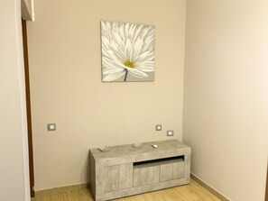 A room with a light-colored wall, a gray console table with a drawer, and a white flower painting above it. - Mariposa - Villaputzu (Villaputzu)