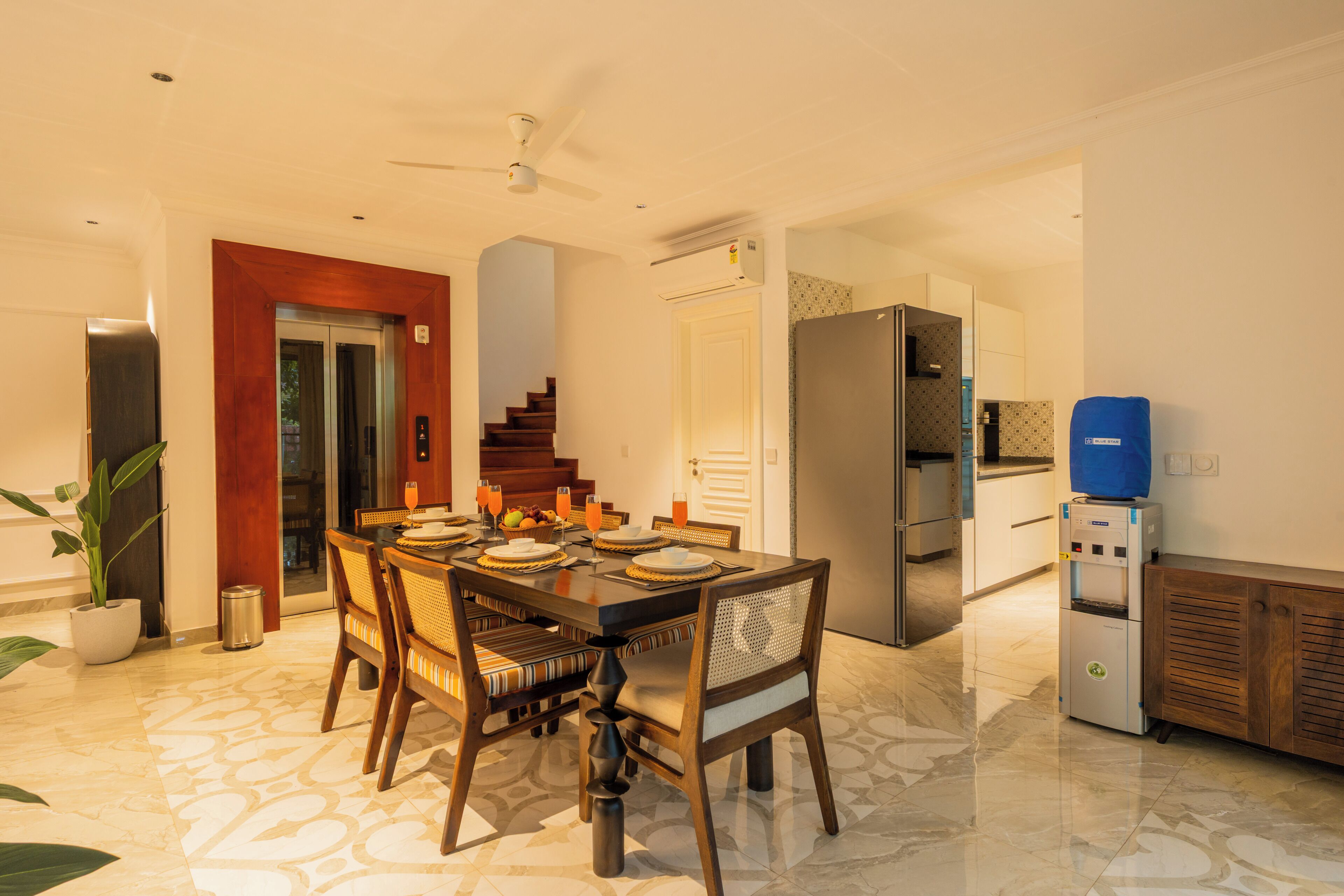 A dining area with a wooden table and chairs, a refrigerator, and a water dispenser.