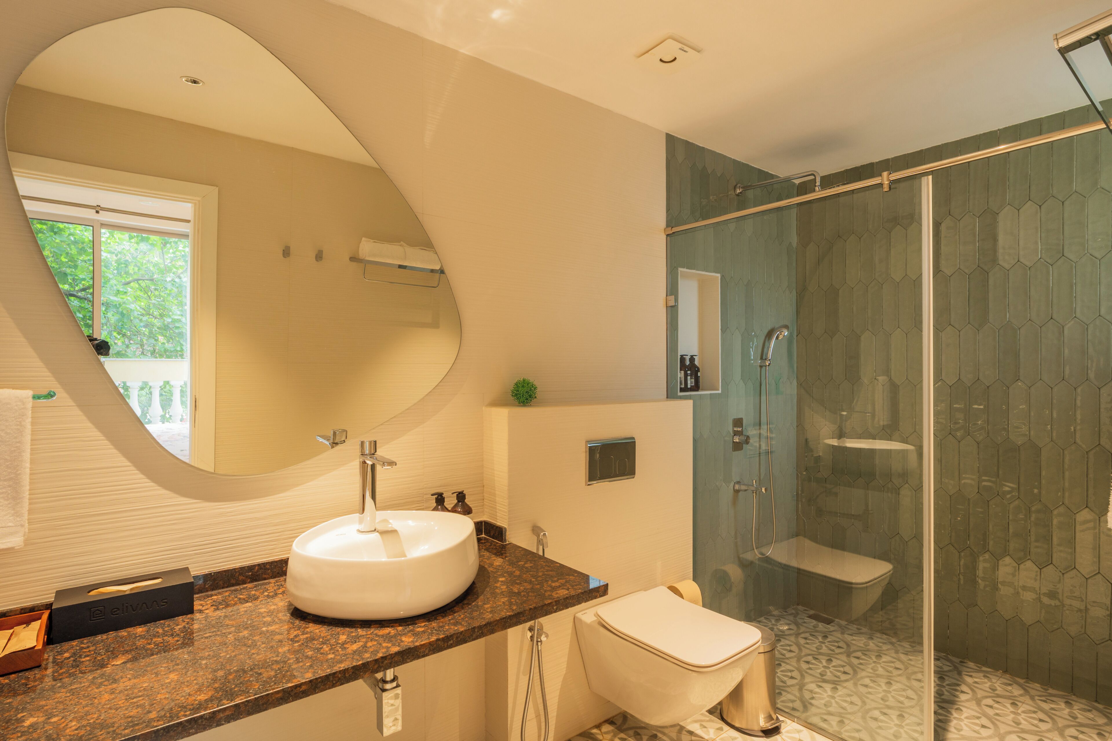 Ein modernes Badezimmer mit rundem Spiegel, Waschbecken, Toilette und einer Duschkabine.
