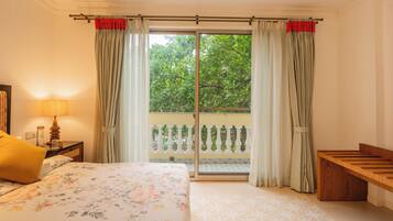 A bedroom with a bed, a bedside table with a lamp, a bench, and a sliding glass door to a balcony.