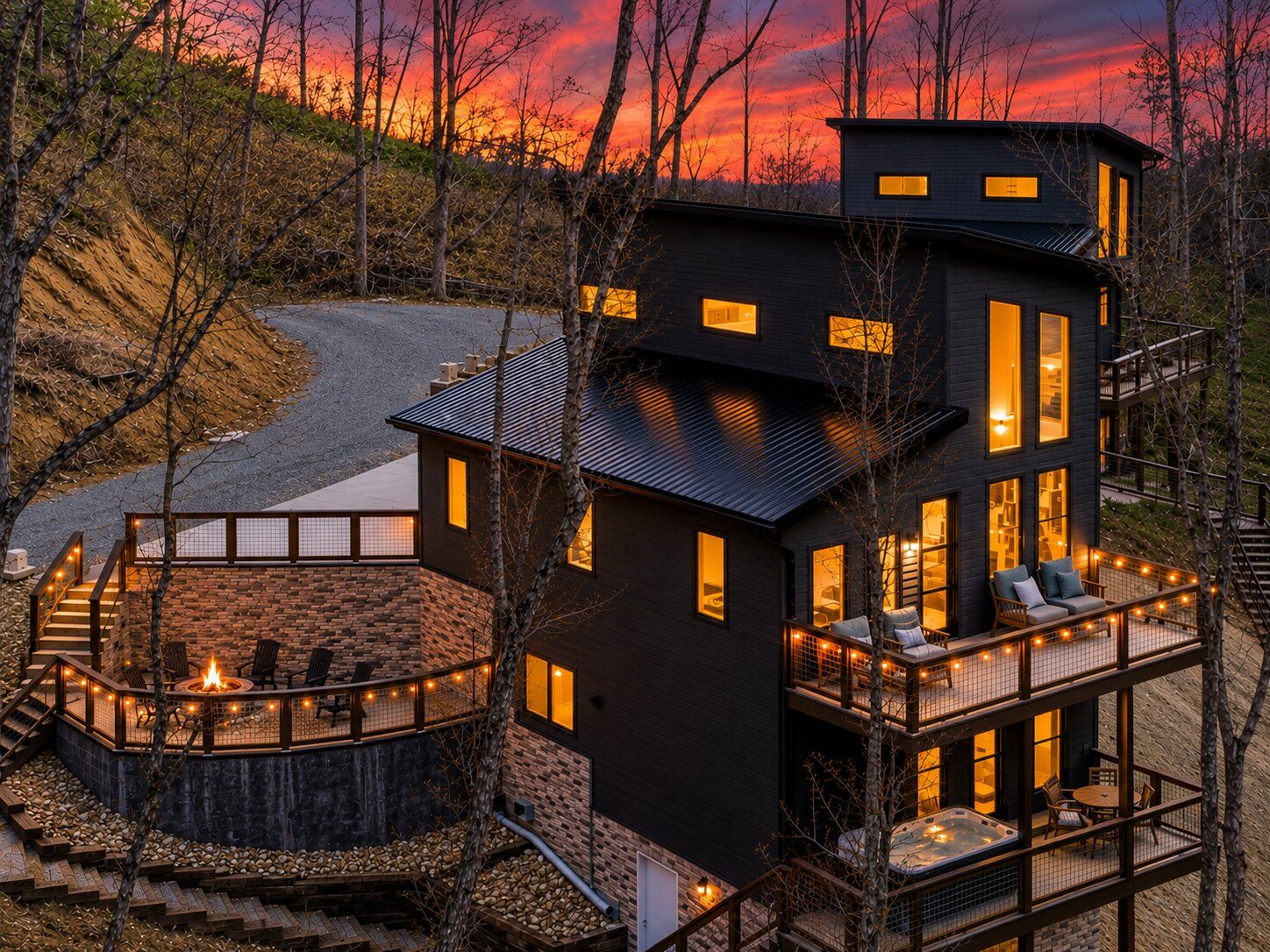 Ein modernes Mehrfamilienhaus mit Feuerstelle, Sitzgelegenheiten im Freien und Blick auf einen Sonnenuntergang.
