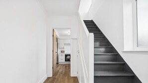 Una escalera conduce a un área de cocina con paredes blancas y piso de madera.