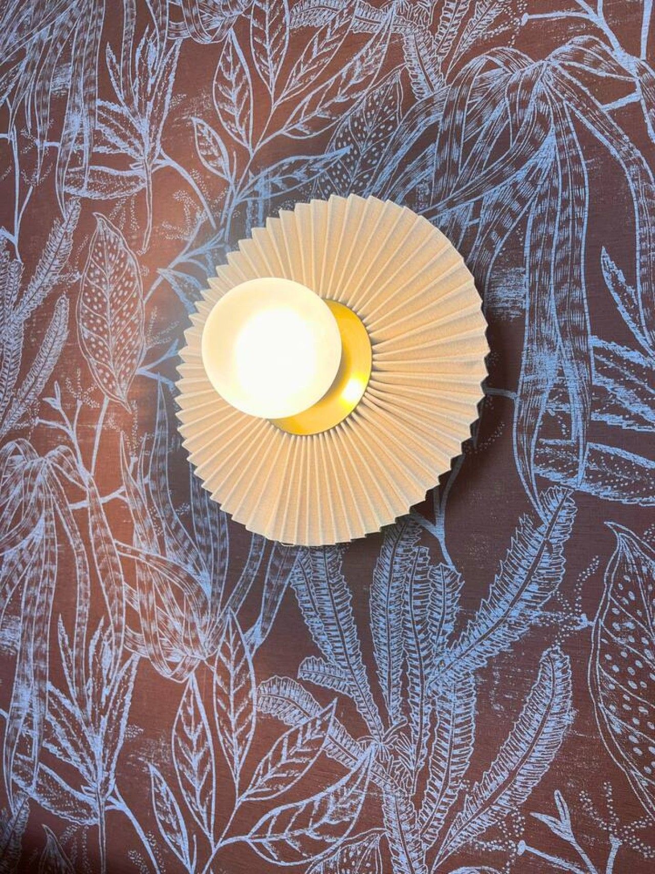 A ceiling with a circular light fixture and a leaf pattern.