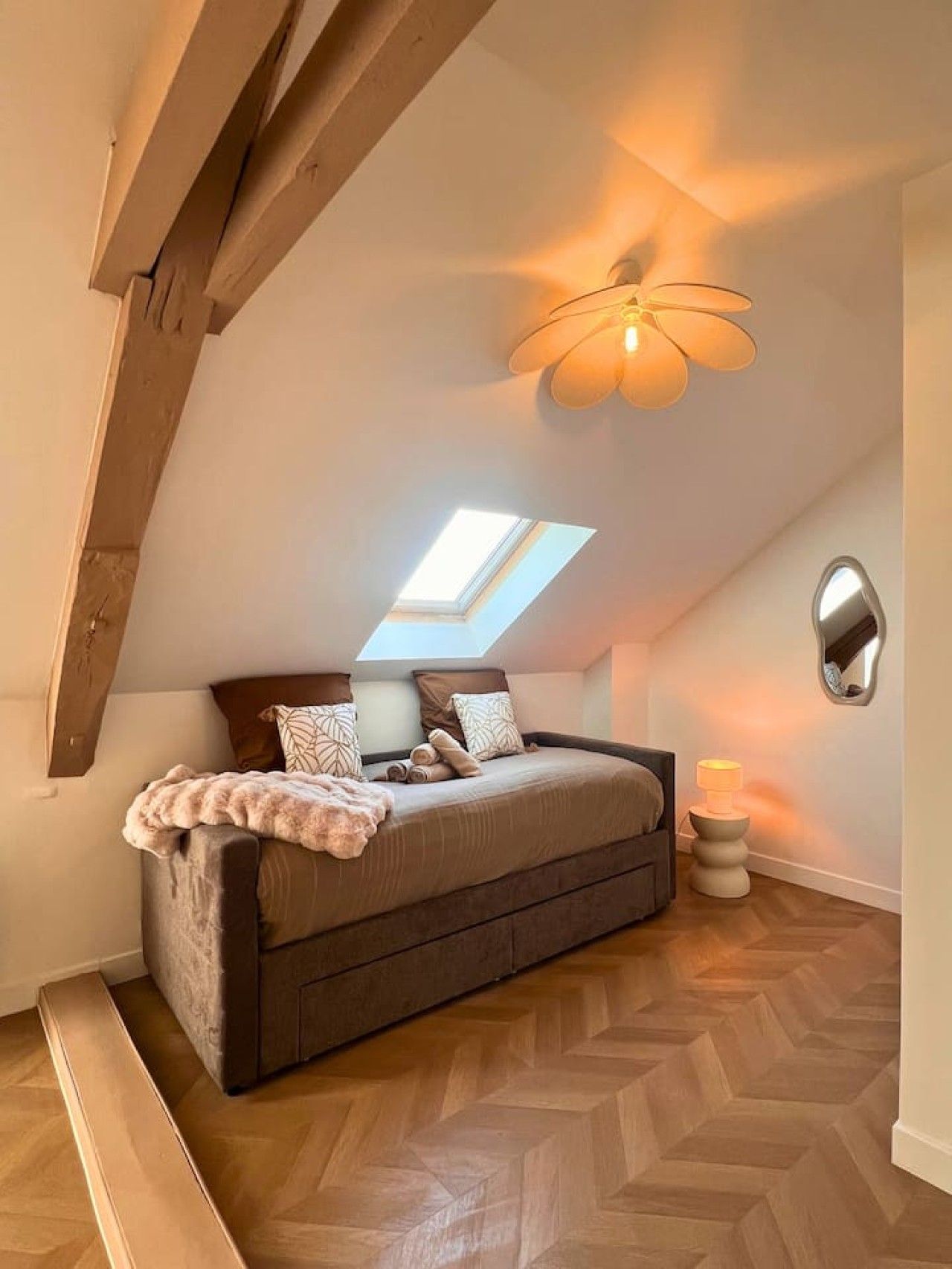 A bedroom with a sloped ceiling, a bed, a skylight, and a ceiling fan.