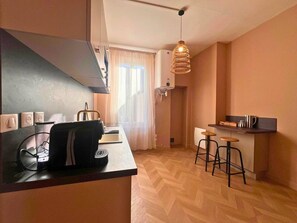 Cozinha compacta com design moderno, equipada com fogão embutido, uma pequena ilha com banquetas e uma luminária pendente.