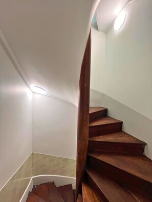 Un escalier en bois avec une rampe courbée, des murs blancs et un éclairage encastré.