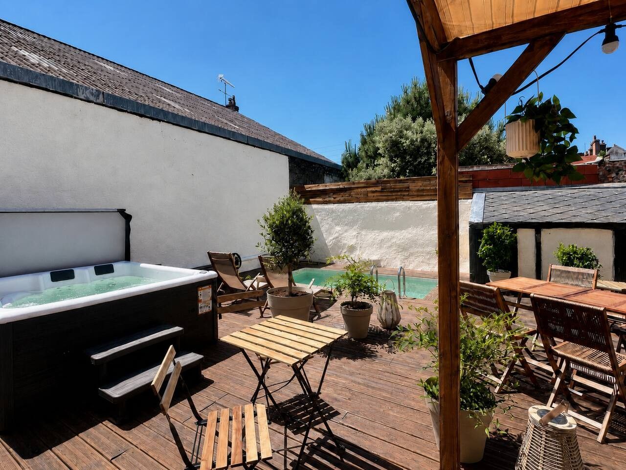 Een terras buiten met een jacuzzi, houten terras en een zithoek.