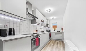 A modern kitchen with white cabinetry, a built-in microwave, and a kettle. - 4|Modern & Cozy 1BD Single Room on Church Road (Bristol)