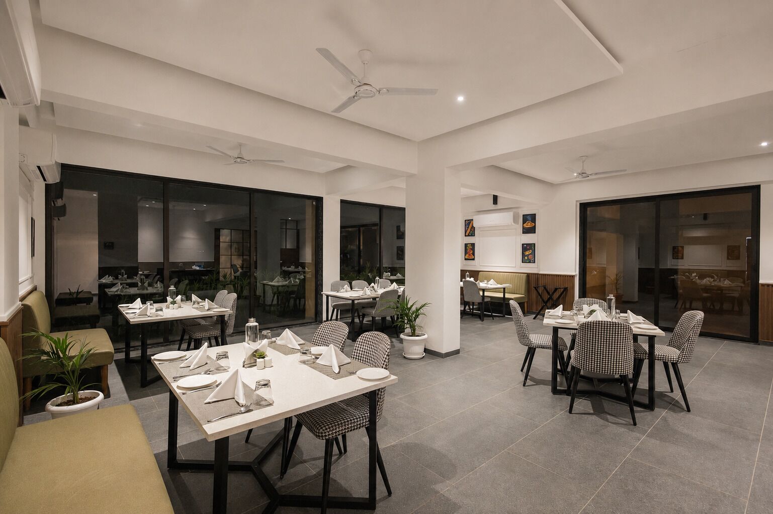 A spacious dining area with multiple tables and chairs, large windows, and ceiling fans.