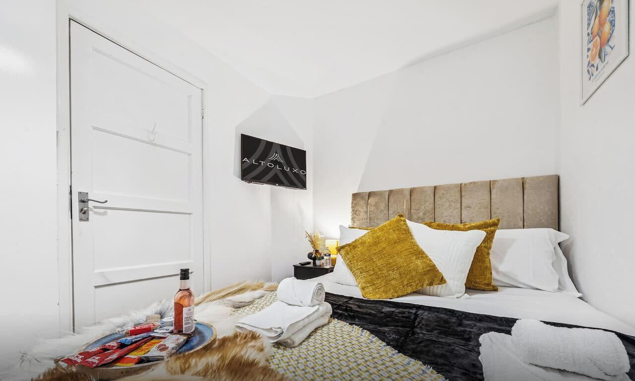 A hotel room with a bed, a nightstand, a white door, and a wall-mounted sign.