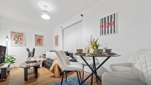 Uma sala de estar moderna com sofá, mesa de jantar, cadeiras e obras de arte nas paredes.