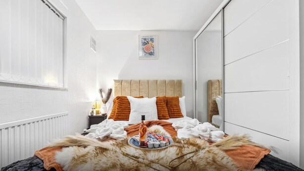 Quarto moderno com cama, mesa de cabeceira, abajur e quadro na parede.
