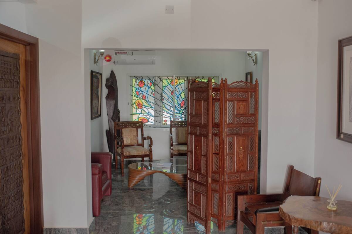 Una habitación con separador de vidrio, muebles de madera y un detalle decorativo en la pared.
