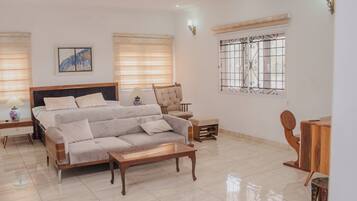 A bedroom with a bed, sofa, wooden coffee table, and a desk with a chair.