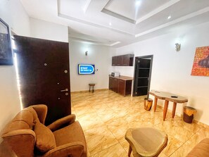 A hotel lobby with a reception desk, a television displaying a 'STAY CONNECT' message, a door, and a seating area with a chair and a small table.