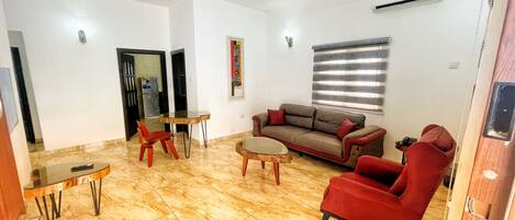 A living room with a sofa, chairs, a coffee table, and a dining table.