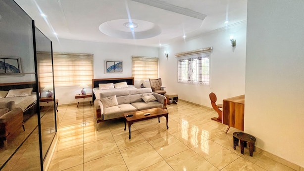 A spacious bedroom with a large bed, a sofa, a small table, and a chair. - Orisun Resort & Gallery (Ibadan)
