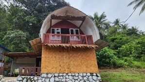 A two-story house with a balcony, a thatched roof, and a stone foundation. - Pondok Wisata Noah (Likupang)