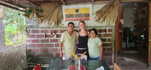 A brick wall with a sign, a table with a vase, and a hanging bell. - Pondok Wisata Noah (Likupang)