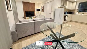 A modern living room with a glass table, sofa, and a TV. - Available Now|Luxury|Contractors|Families|Groups (Easton)