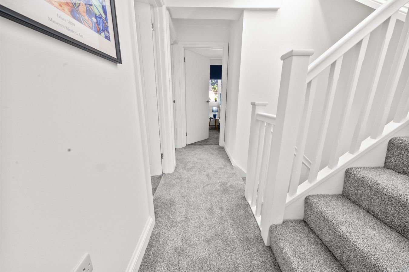 A hallway with carpeted stairs and white walls.