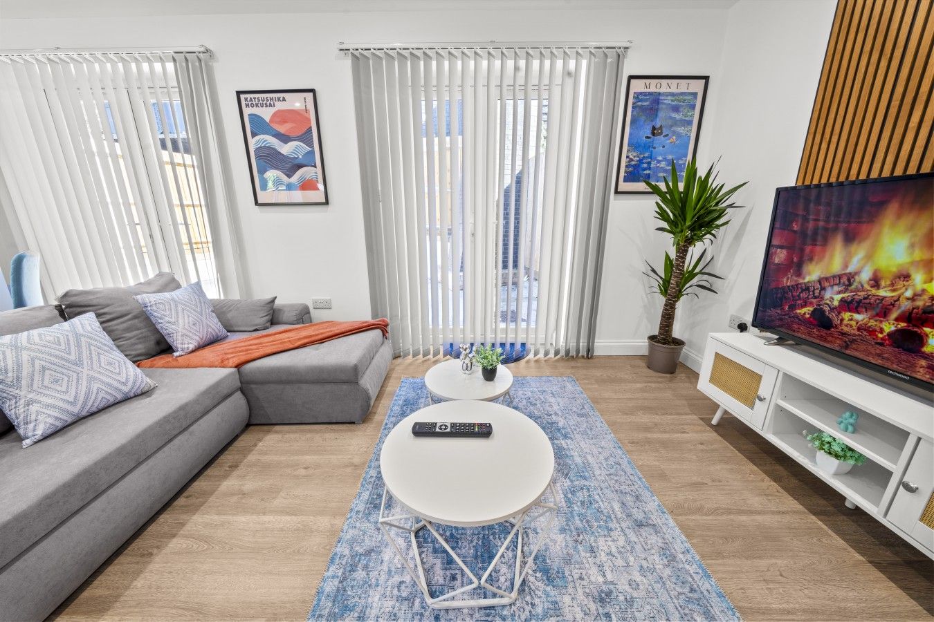 A modern living room with a grey sofa, a white coffee table, and a television on a wooden cabinet.