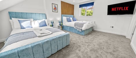 A bedroom with two beds, a TV, and a view of the outdoors.