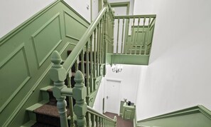 A staircase with green railings and a carpeted landing.